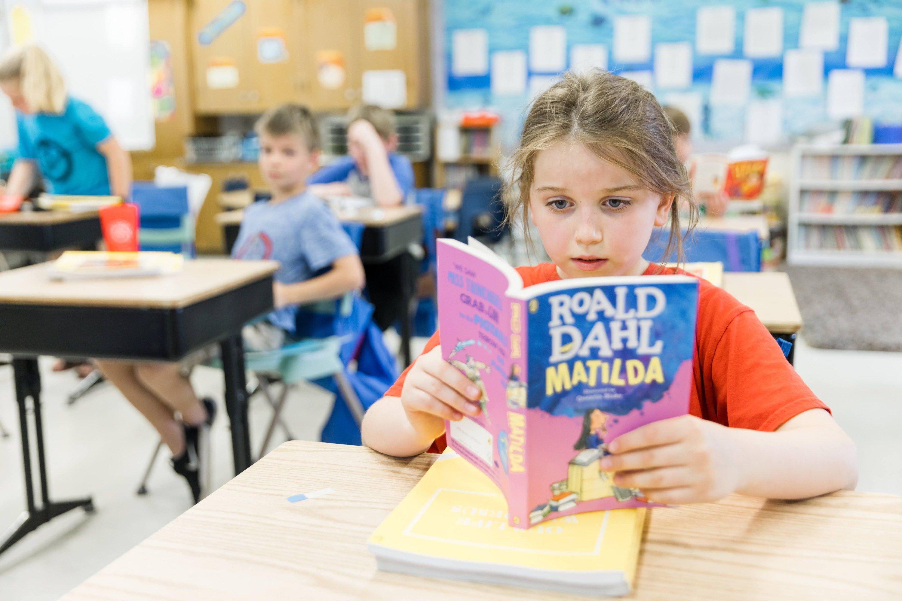 A student reads Roald Dahl's Matilda at her desk.