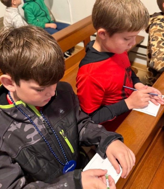 Two students writing notes while sitting in a church pew.
