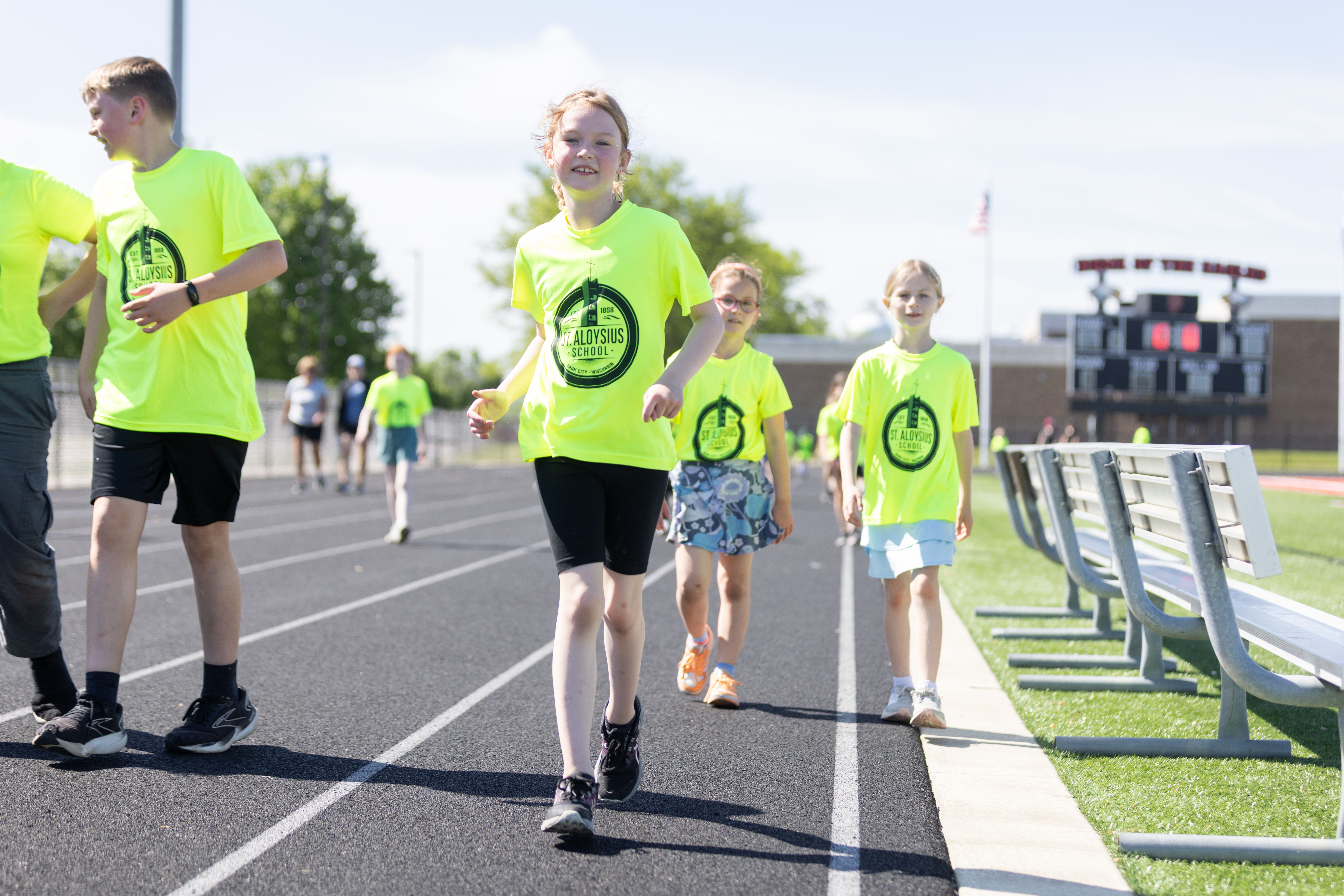 Students in bright St. Aloysius T-shirts walk the track during the Walk-a-thon.