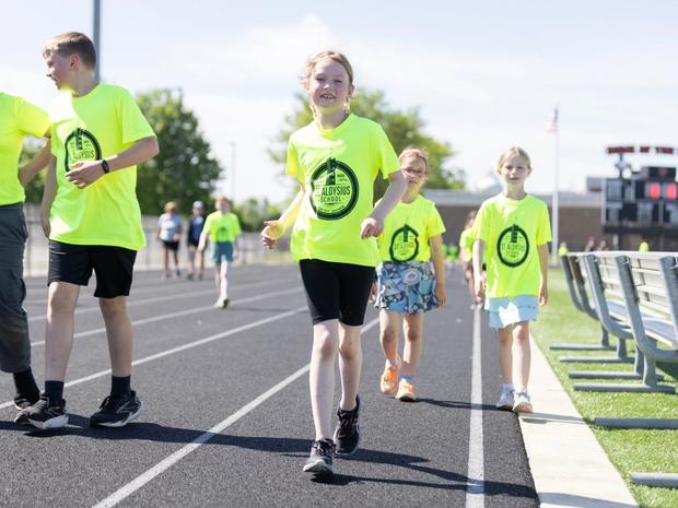 Students in bright St. Aloysius T-shirts walk the track during the Walk-a-thon.