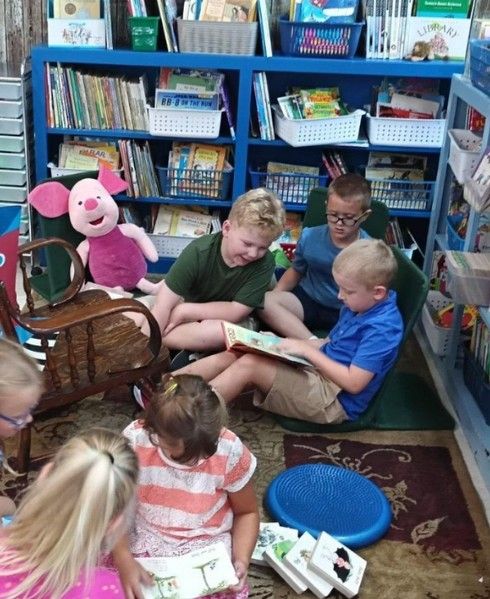 Students reading books together on the classroom rug.