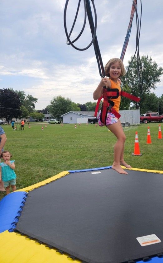 A child in a harness jumping on a bungee trampoline.