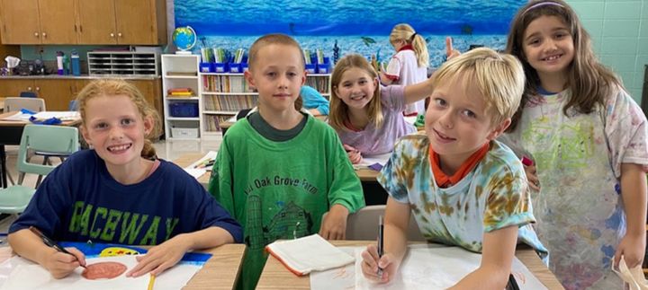 Smiling students sitting together at a classroom table.