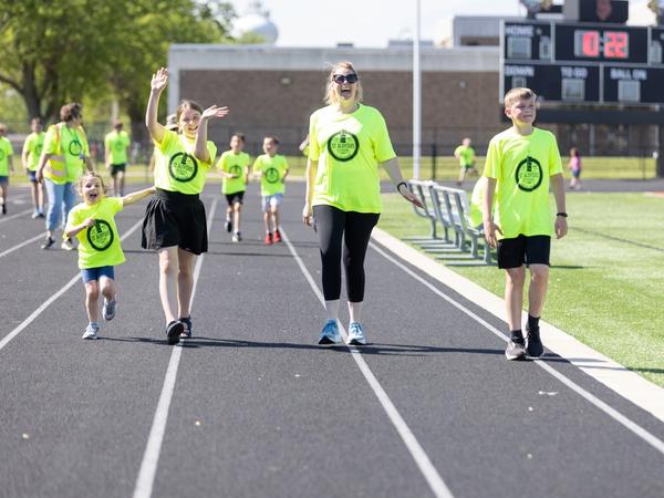 Students and an adult wave and laugh as they walk the track together at the 2025 Walk for Goodness' Sake.