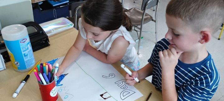 Two first graders drawing a Creation poster together.