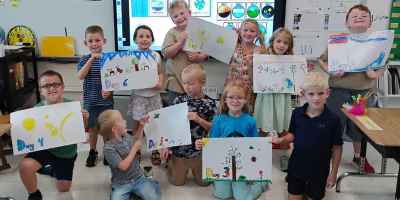First graders holding up their posters of the days of Creation.