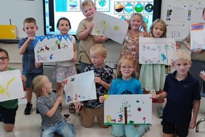 First graders holding up their posters of the days of Creation.