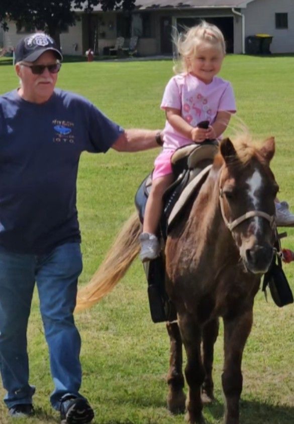 A man leading a young child on a pony ride.