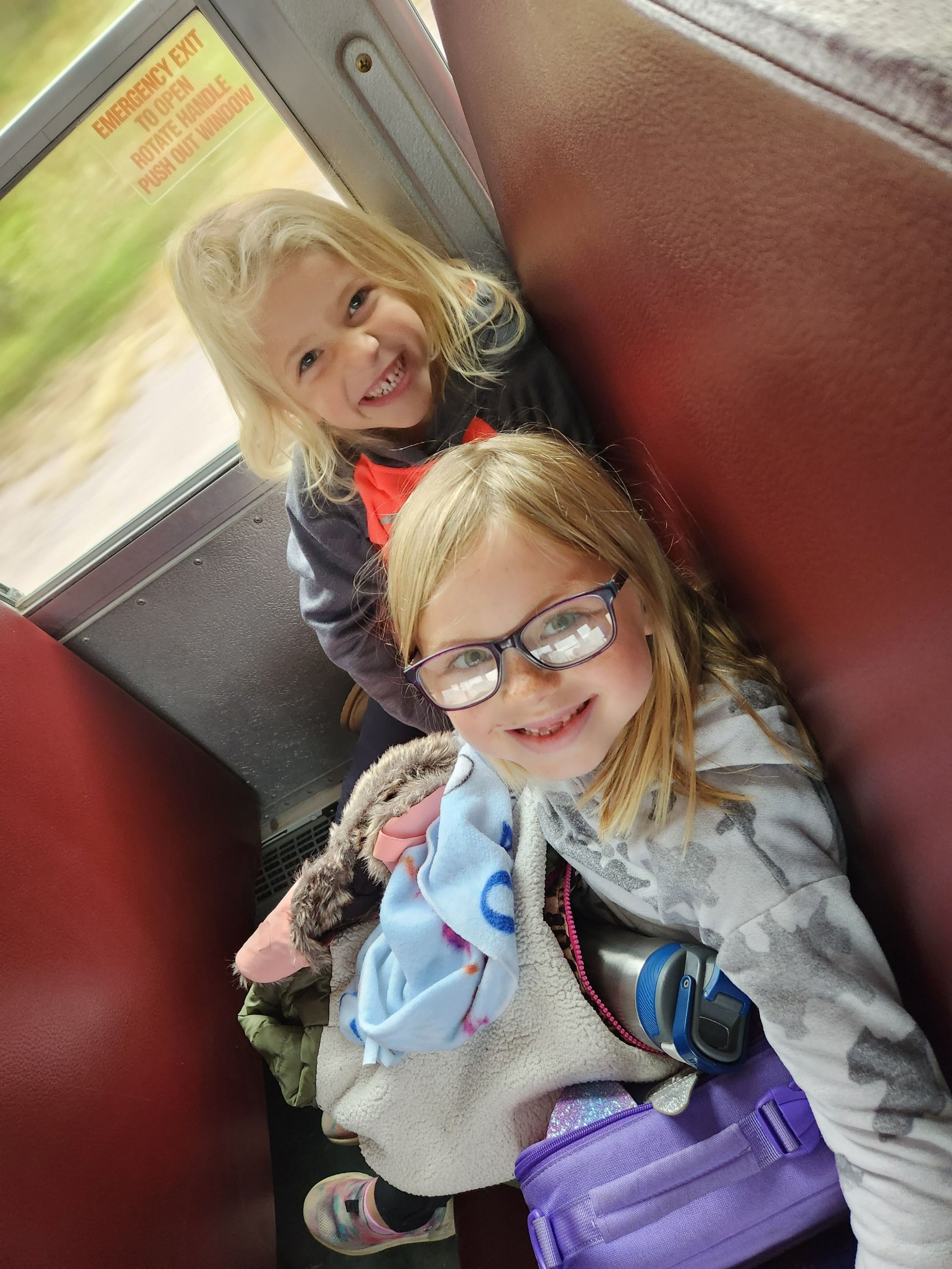 Eve Sauter (K) and Kensi Hrubi (1) show how happy they are to ride the bus together.