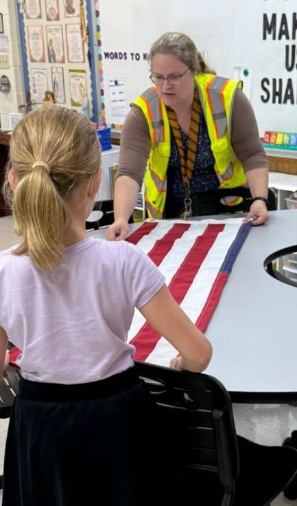 A teacher showing a student how to fold the American flag.