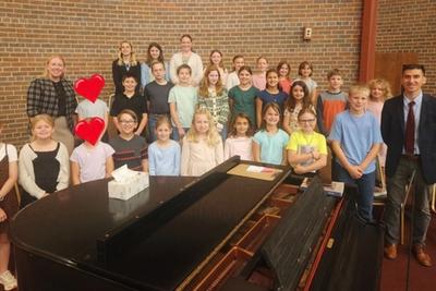 Mass Choir members gathered around the piano with their teachers.