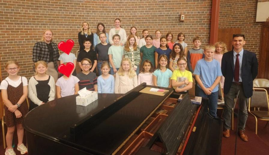 Mass Choir members gathered around the piano with their teachers.