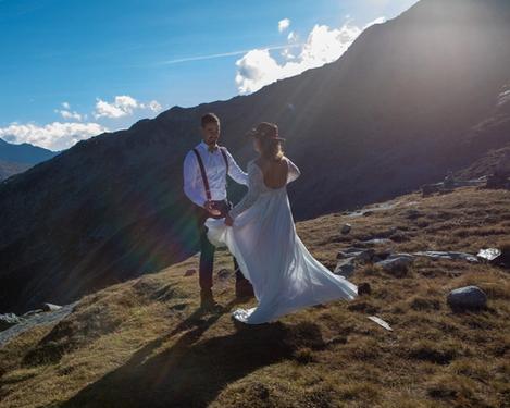 Braut und Bräutigam tanzen in den Bergen bei untergehender Sonne