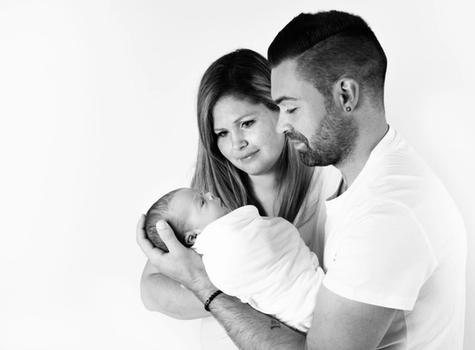 Parents holding their baby wrapped in white cloth, black and white image
