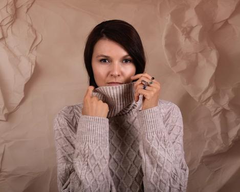 Portrait of a dark-haired woman with a beige-coloured turtleneck jumper