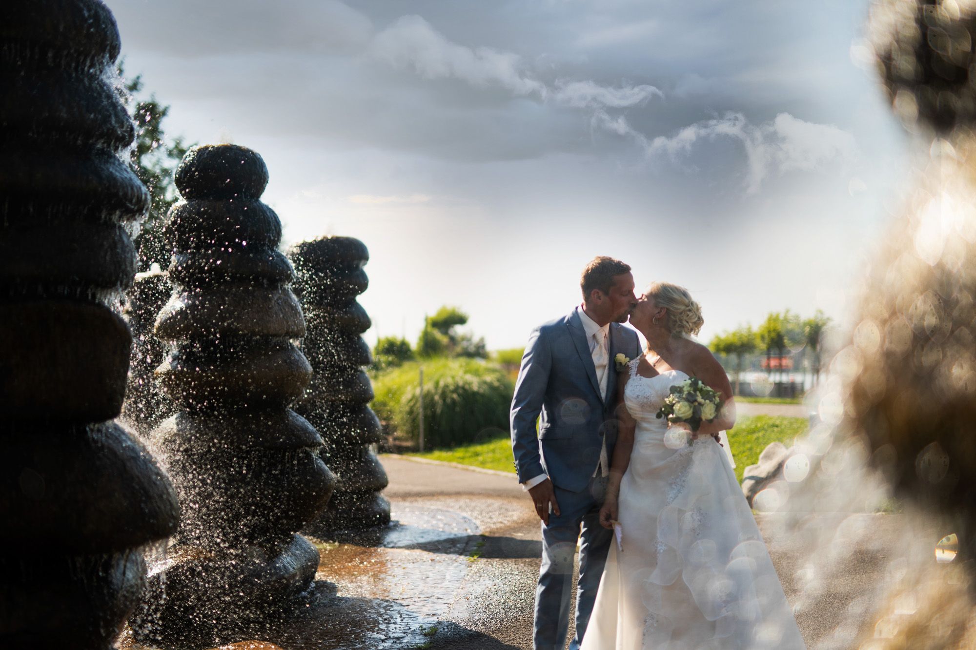 Sich küssendes Brautpaar umgeben von Springbrunnen in form von gestapelten Steinen