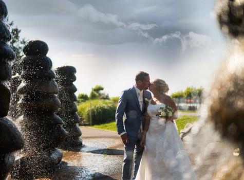 Kissing bride and groom surrounded by fountains in the form of stacked stones