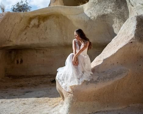 Bride sitting alone on a stone of a stone cave 