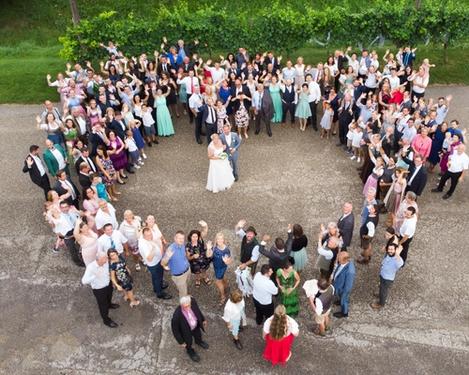 Drone shot of the entire wedding guests with bride and groom in the middle