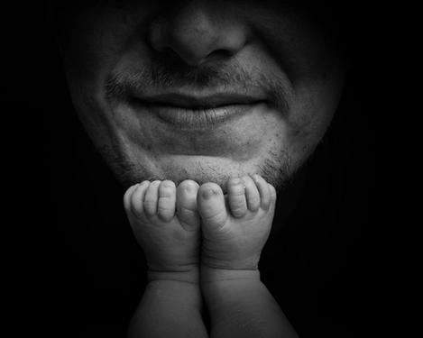 Detail von Babyfüßchen auf Papas Kinn; sw-Bild