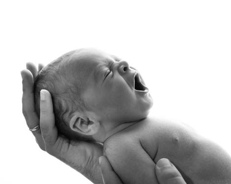 Yawning newborn baby in profile view against white background