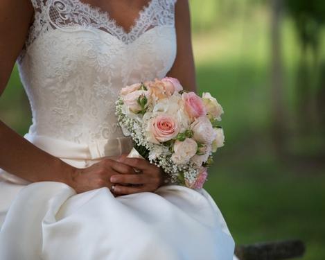 Oberkörper einer Braut mit hellrosa Brautstrauß in den Weingärten