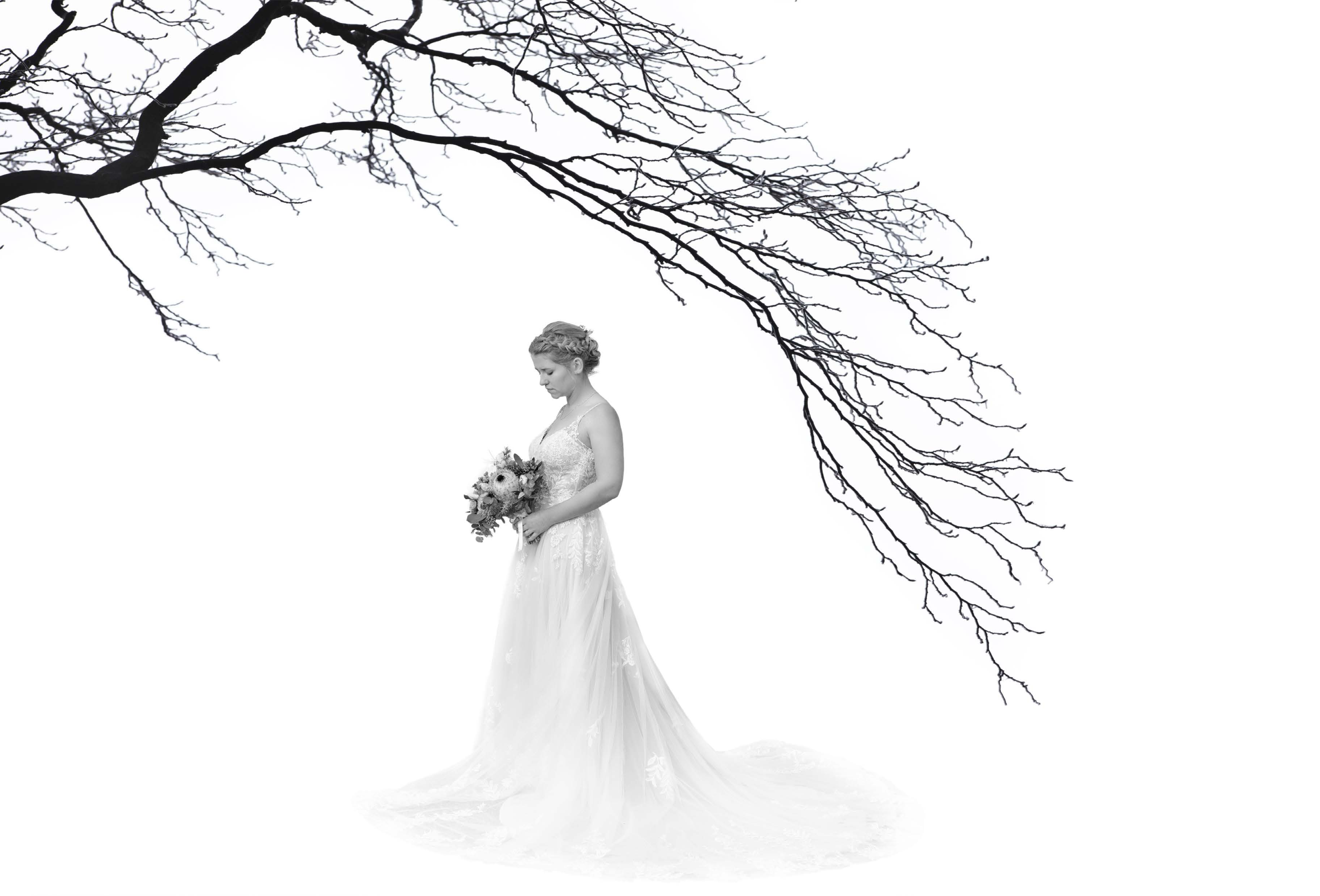 Braut in Seitenansicht vor weitem Hintergrund und einem Ast im Vordergrund