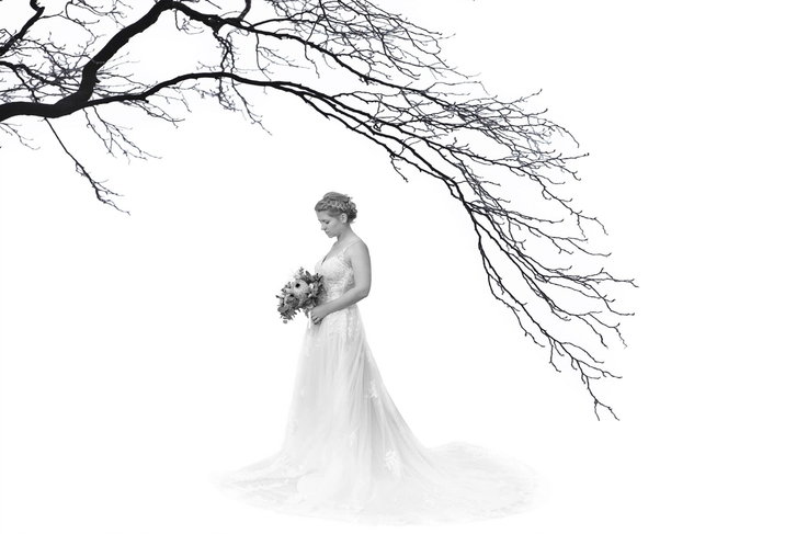 Braut in Seitenansicht vor weitem Hintergrund und einem Ast im Vordergrund
