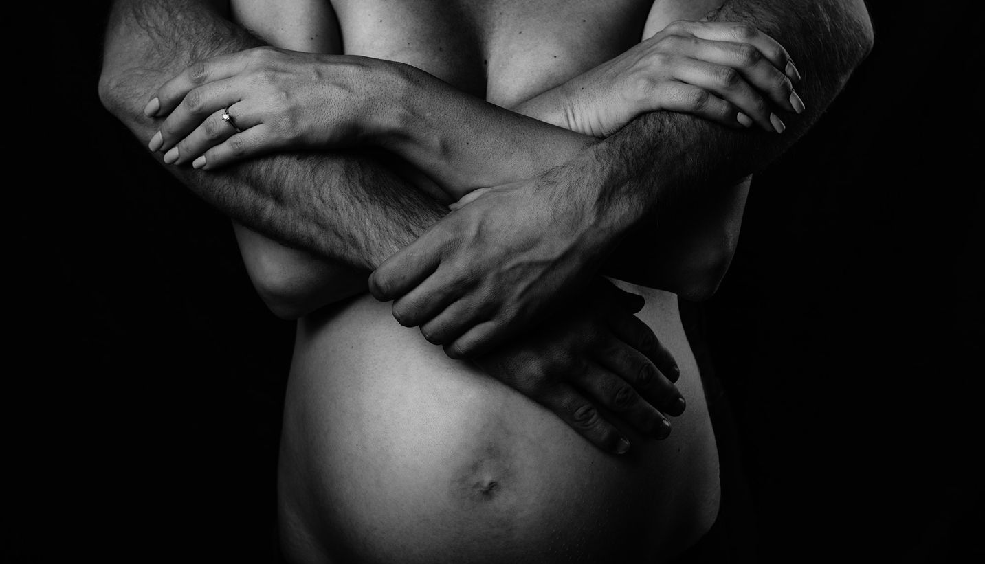 Pregnant woman belly with hands clasped and that of her partner