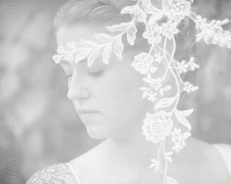 Side view of the bride looking down and veil with flower ornaments in front of her face, b/w image