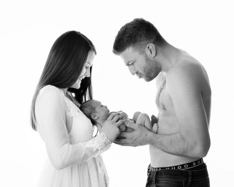 Newborn baby in hands of father and mother against white background