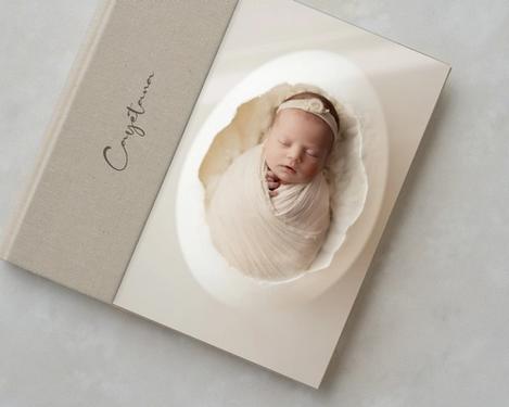 Fotobuch mit Monogramm und Foto von einem Baby hinter Acrylglas in Naturfarben