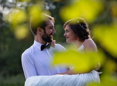 Brautpaar lächelt sich an, romanische Szene inmitten von grünen Blättern