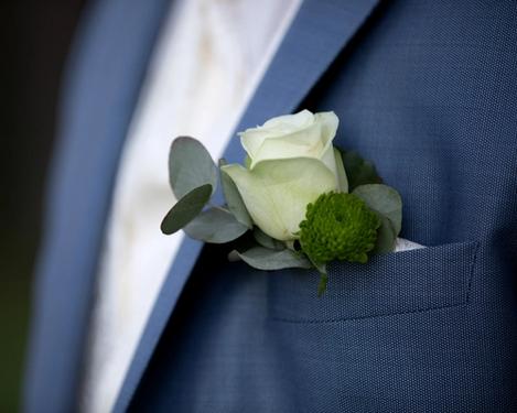 Weiße Rose als Bräutigamschmuck am blauen Anzug