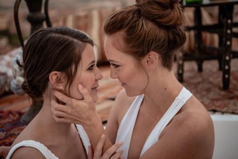 A same-sex female couple looks into each other's eyes.