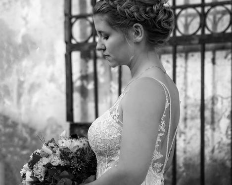 Side view of the bride looking down to the bouquet, in front of an iron gate