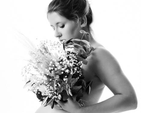 Schwangere Frau in Portraitansicht mit Blumenstrauß vor dem Oberkörper