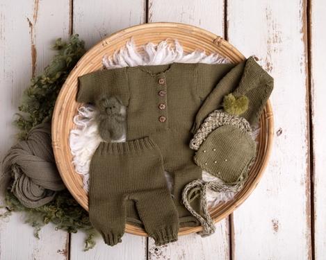 Olivgrüner Strampler mit Mützen, Teddy  und Tuch in einer Bambusschale für die Neugeborenenfotografie