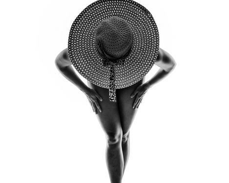 Woman with hat in the backlight, studio shot