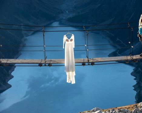 Wedding dress hanging on a suspension bridge over a lake