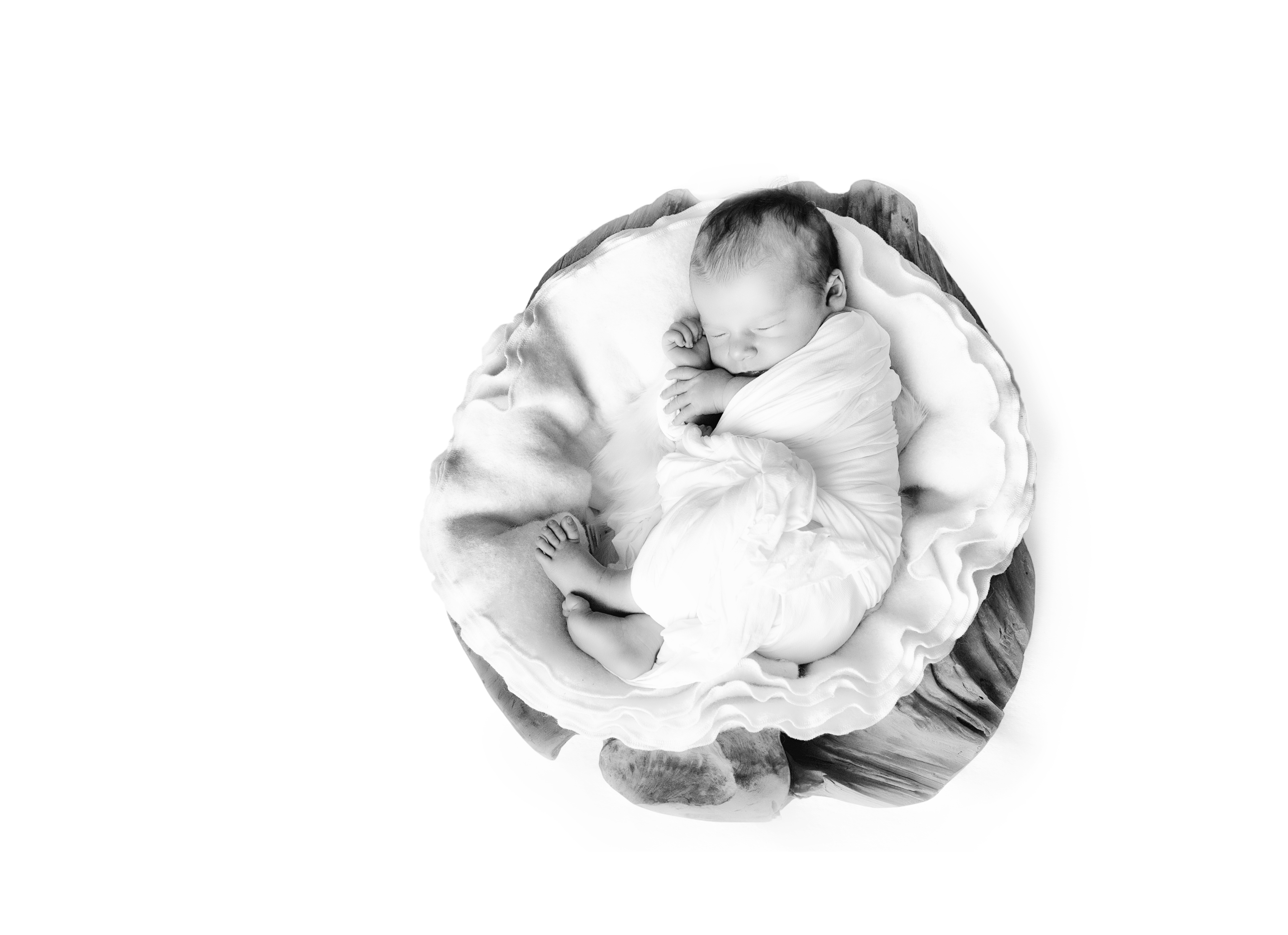 Schlafendes, in Tücher gewickeltes Baby liegt in einer Holzschale