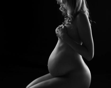 Silhuette of a sitting pregnant woman in back light