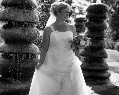 Bride standing amidst stone fountains in backlight, b/w image