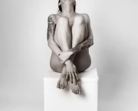 Woman sitting on white stool and head falling backwards, studio shot