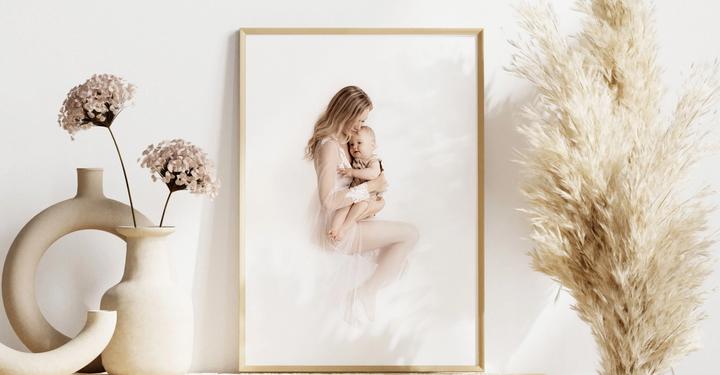 Wandbild mit Holzrahmen an einen einem mit Vasen und Blumen dekorierten Tisch gelehnt