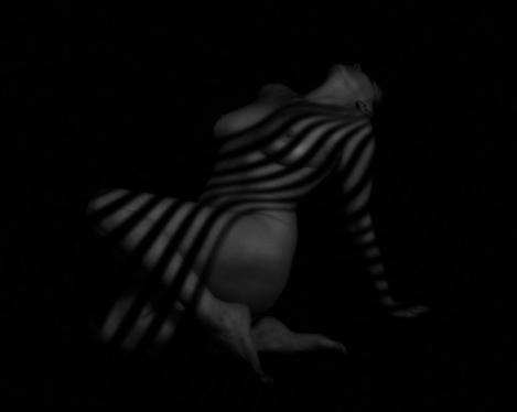 Image of a half-lying woman with shadow pattern on her body, b/w picture