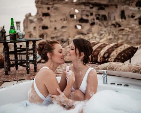 Ein gleichgeschlechtliches weibliches Paar sitzt in einer Outdoor-Badewanne und hat Spaß.