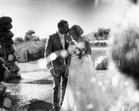 Kissing bridal couple in front of a fountain, b/w picture