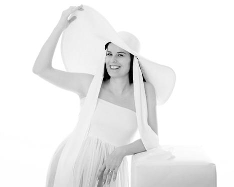 Pregnant woman in white dress and hat against white background