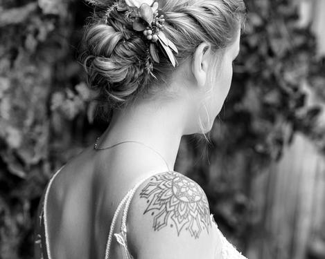 Portrait of the bride from behind with her hair pinned up and decorated with flowers, b/w picture